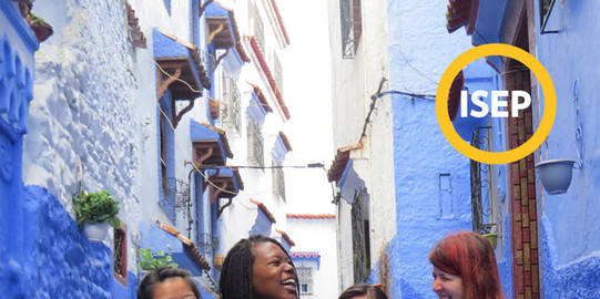 Vier Personen sehen zwischen blauen Gebäuden und lachen